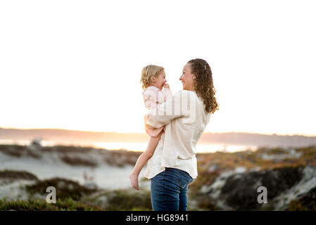 Glückliche Mutter Tochter auf auffangene gegen klaren Himmel stehend betrachten Stockfoto