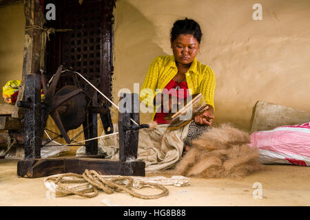 Einheimische Frau spinnt Schafwolle mit traditionellen Spinnrad vor Haus, Ghandruk, Distrikt Kaski, Nepal Stockfoto