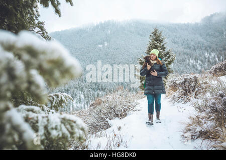 Frau mit Welpen während des Gehens auf schneebedeckten Feld Stockfoto