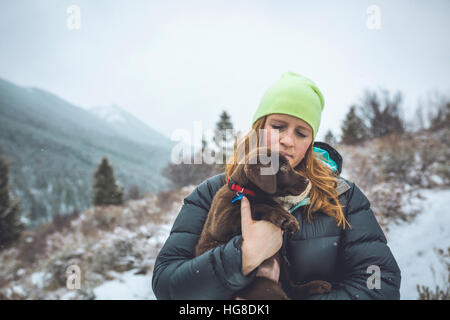 Frau mit Chocolate Labrador stehend gegen Himmel im winter Stockfoto