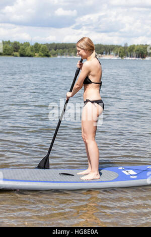 Seitenansicht der Trägerin Bikini Paddling in See Stockfoto
