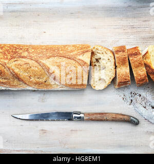 In Scheiben geschnitten Brot mit Messer auf Holztisch Stockfoto