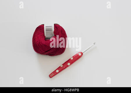 Rote Kugel aus Wolle mit rot Neuheit Häkelnadel auf weißem Hintergrund Stockfoto