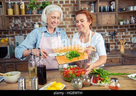 Zwei lächelnde Frauen Gemüsesalat gemeinsam kochen Stockfoto