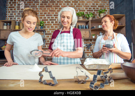 Großmutter und Enkelin Sichtung Mehl für Cookies in Küche Stockfoto