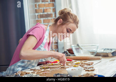 Teenager-Mädchen trägt Schürze und Sahnehäubchen Weihnachtsplätzchen Stockfoto