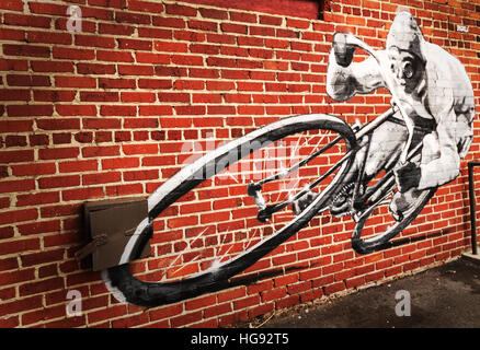 Wandbild eines Mannes mit dem Fahrrad, auf einer Mauer Stockfoto