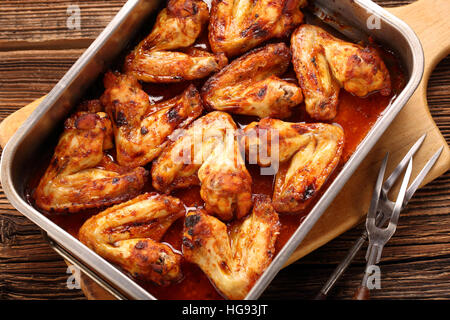 Hühnerflügel gebacken in einer Pfanne auf hölzernen Hintergrund Stockfoto