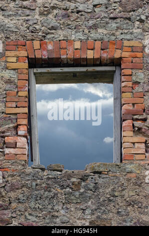 Zerstörten rustikale Kalkstein Felsen Schutt Wand Mauerwerk Mauerwerk Ruinen und rotem Backstein Fensteröffnung der Blende mit verwitterten alten Alter Holzrahmen zeigen Stockfoto