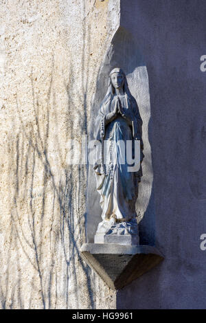 Madonna auf Sockel mit Sonne und Schatten an Wand Stockfoto