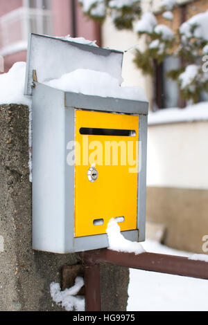 Schneebedeckte gelben Briefkasten vor einem Haus Stockfoto