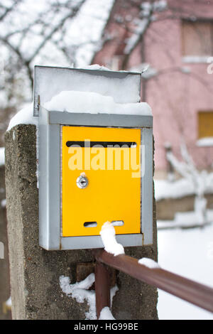 Schneebedeckte gelben Briefkasten vor einem Haus Stockfoto