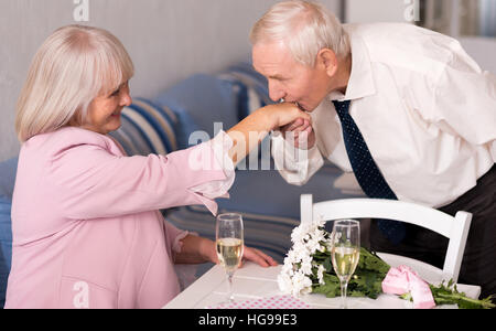 Aufmerksame älterer Mann seine Womans Hand küssen Stockfoto