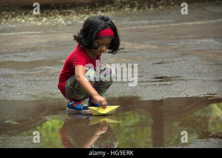 Indische Mädchen spielen mit Papierboot während der Regenzeit Stockfoto