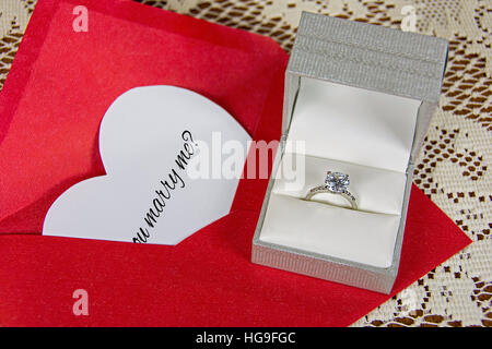 Heiratsantrag auf weißen Herzen im roten Umschlag mit Solitär Diamant ring in satin-box Stockfoto