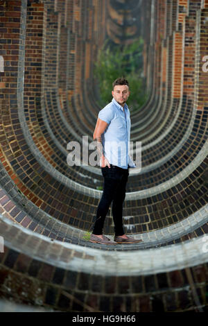 Sänger, posiert Songwriter Jamie Mathias mit seiner Gitarre für ein Shooting an der Ouse Valley-Viadukt, Sussex, UK. Stockfoto