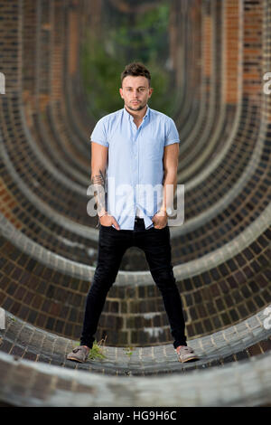 Sänger, posiert Songwriter Jamie Mathias mit seiner Gitarre für ein Shooting an der Ouse Valley-Viadukt, Sussex, UK. Stockfoto