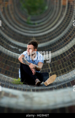 Sänger, posiert Songwriter Jamie Mathias mit seiner Gitarre für ein Shooting an der Ouse Valley-Viadukt, Sussex, UK. Stockfoto