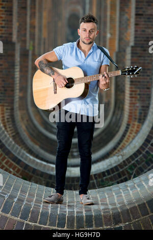 Sänger, posiert Songwriter Jamie Mathias mit seiner Gitarre für ein Shooting an der Ouse Valley-Viadukt, Sussex, UK. Stockfoto