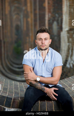 Sänger, posiert Songwriter Jamie Mathias mit seiner Gitarre für ein Shooting an der Ouse Valley-Viadukt, Sussex, UK. Stockfoto