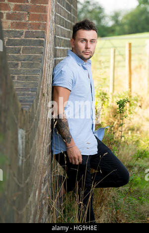 Sänger, posiert Songwriter Jamie Mathias mit seiner Gitarre für ein Shooting an der Ouse Valley-Viadukt, Sussex, UK. Stockfoto