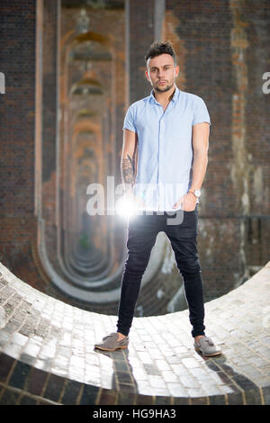 Sänger, posiert Songwriter Jamie Mathias mit seiner Gitarre für ein Shooting an der Ouse Valley-Viadukt, Sussex, UK. Stockfoto