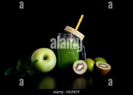 Gesunden grünen Smoothie und Zutaten auf schwarz - Spinat, Apfel und Kiwi. Superfood, Entgiftung und gesunde Ernährung. Stockfoto