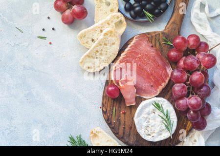 Vorspeise-Teller mit frischem Baguette, Wurst, Trauben, Käse und Oliven. Antipasti oder Tapas-Konzept. Ansicht von oben, Textfreiraum Stockfoto