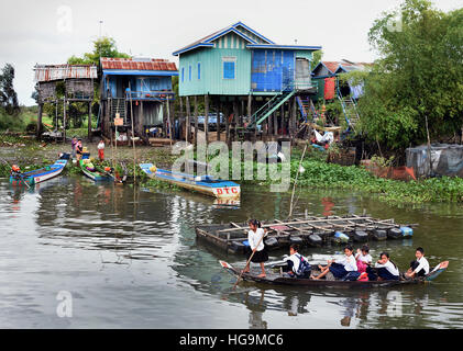 Kleines Boot mit Schulkindern entwässert schwimmende Dorf der Sangkhae - Sangker River Battambang Provinz Cambodia.The Tonle Sap See (reichsten See zum Angeln in der Welt) in den Mekong-Fluss in Phnom Penh. Die kambodschanische Bevölkerung hat auch für das einzigartige Ökosystem des Sees mit schwimmenden angepasst (Fischer-Fischerei) Dörfer und gestelzt Häuser. Stockfoto