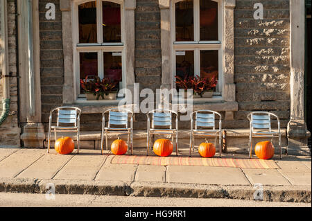 Ein Satz von fünf Aluminium Chairs aufgereihten auf dem Bürgersteig mit orange Kürbisse unter ihnen in Old Quebec City, Kanada. Stockfoto