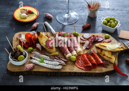 Mischung aus verschiedenen Snacks und Vorspeisen. Spanische Tapas auf einem schwarzen Stein Hintergrund.  Bar. Platz für Text. Deli, Sandwiches, Oliven, Wurst, Sardellen, Käse, Schinken, Pfeffer, Tomaten. Ansicht von oben Stockfoto