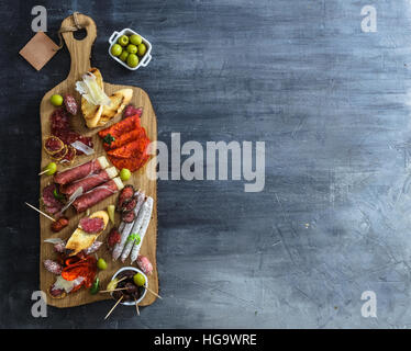 Typische spanische Tapas-Konzept. beinhalten verschiedene Scheiben Schinken, Chorizo, Salami, Schalen mit Oliven, Paprika, Sardellen, würzige Kartoffeln, pürierte Kichererbsen auf einem Holztisch. Exemplar Stockfoto