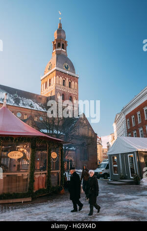 Riga, Lettland - 1. Dezember 2016: Passanten in der Nähe von Weihnachtsmarkt am Domplatz mit Rigaer Dom. Handelshäuser mit Verkauf von Weihnachten G Stockfoto