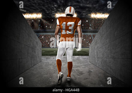 Football-Spieler mit einer orangefarbenen Uniform aus einem Stadion Tunnel gehen. Stockfoto