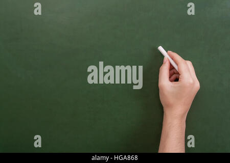 Nahaufnahme von einem Lehrer oder Schüler Hand hält einen Kreide-Stick zu schreiben auf eine leere grüne Tafel mit Exemplar Stockfoto