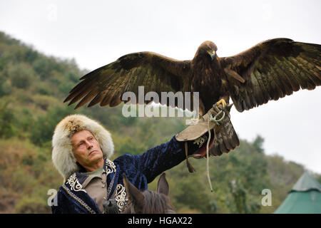 Vogel-Trainer auf Reiten hält ein Steinadler mit Verbreitung Flügel an a. Raptor Center Almaty Kasachstan Stockfoto