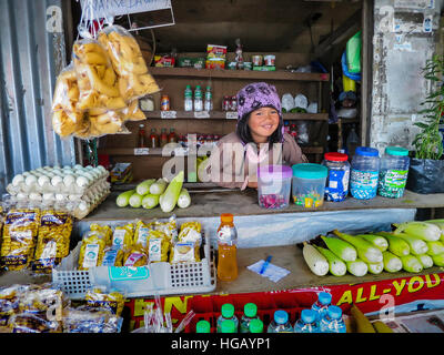 Ein junges Mädchen Ifugao arbeitet an einer am Straßenrand Convenience-Store in der Cordillera Bergen der nördlichen Insel Luzon, Philippinen. Stockfoto