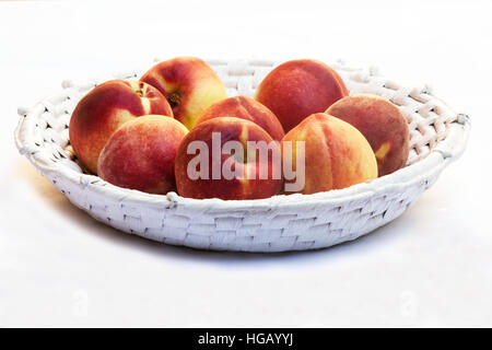 Frische Pfirsiche in einem Korb auf weißem Hintergrund Stockfoto