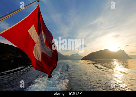 Schweizer Flagge auf Tourenboot Kreuzfahrt Vierwaldstätter See, Sonnenuntergang über die Alp Berge, Schweiz Stockfoto