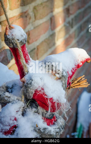 Schnee bedeckten Santa Claus Figur Klettern auf einer roten Backsteinmauer, Deutschland Stockfoto