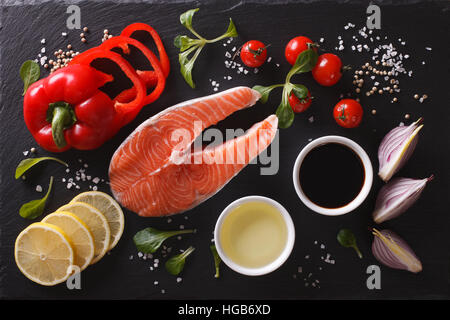 Roher Lachs Steak und Zutaten auf einem Schneidebrett schwarz. Horizontale Ansicht von oben Stockfoto