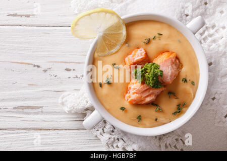 Lachs-Cremesuppe mit Zitrone in einer weißen Schüssel auf dem Tisch. horizontale Ansicht von oben Stockfoto