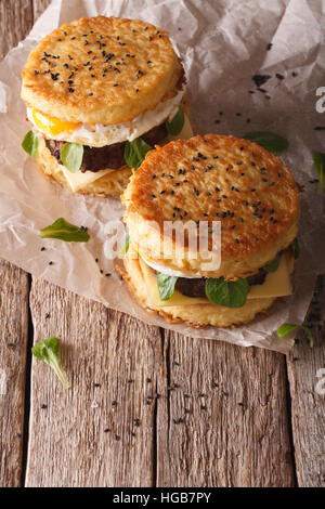 Ramen-Burger mit Rindfleisch und Ei auf einem Papier auf einem Holztisch. vertikale Stockfoto