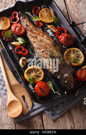 Fischgerichte: Forelle mit Gemüse auf dem Grill pan close-up auf dem Tisch. vertikale Stockfoto