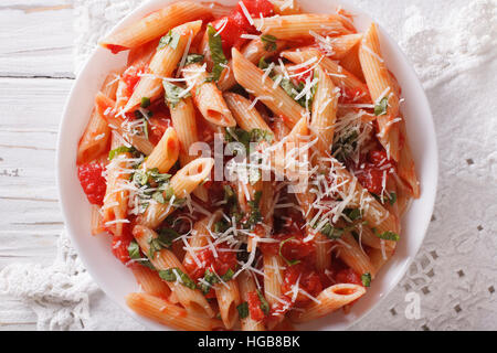 Heiße Nudeln Arrabbiata mit Parmesan und Kräutern Closeup auf einem Teller. Horizontale Ansicht von oben Stockfoto