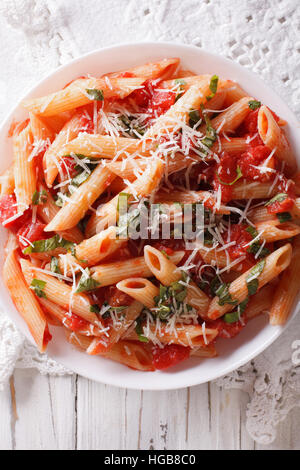 Heiße Nudeln Arrabbiata mit Parmesan und Kräutern Closeup auf einem Teller. vertikale Ansicht von oben Stockfoto