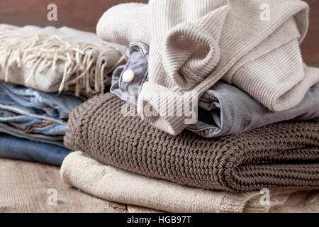 Stapel von warme Kleidung, Stapel von Jeans auf dem alten hölzernen Hintergrund Stockfoto