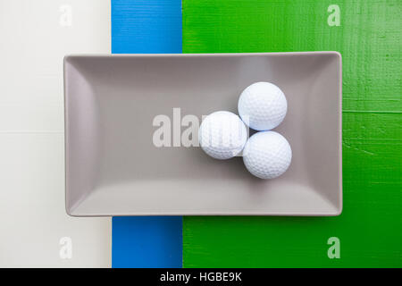 Graue Keramik Teller mit Golf-Ausrüstungen auf über weißen, blauen und grünen Holztisch, Rechteck Schale Stockfoto