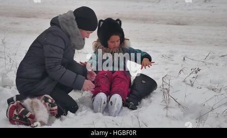 MOM bringt auf Skates Tochter Winterschnee, Urlaub mit der Familie Mädchen Stockfoto