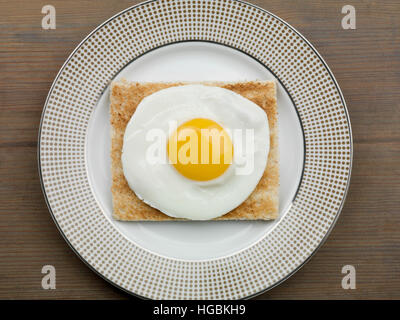 Ein frisch zubereitetes Frühstück von einem Spiegelei auf Toast oder leichtes Mittagessen Sunny Side Up serviert auf einem Teller mit keine Menschen als Flach Zusammensetzung Stockfoto